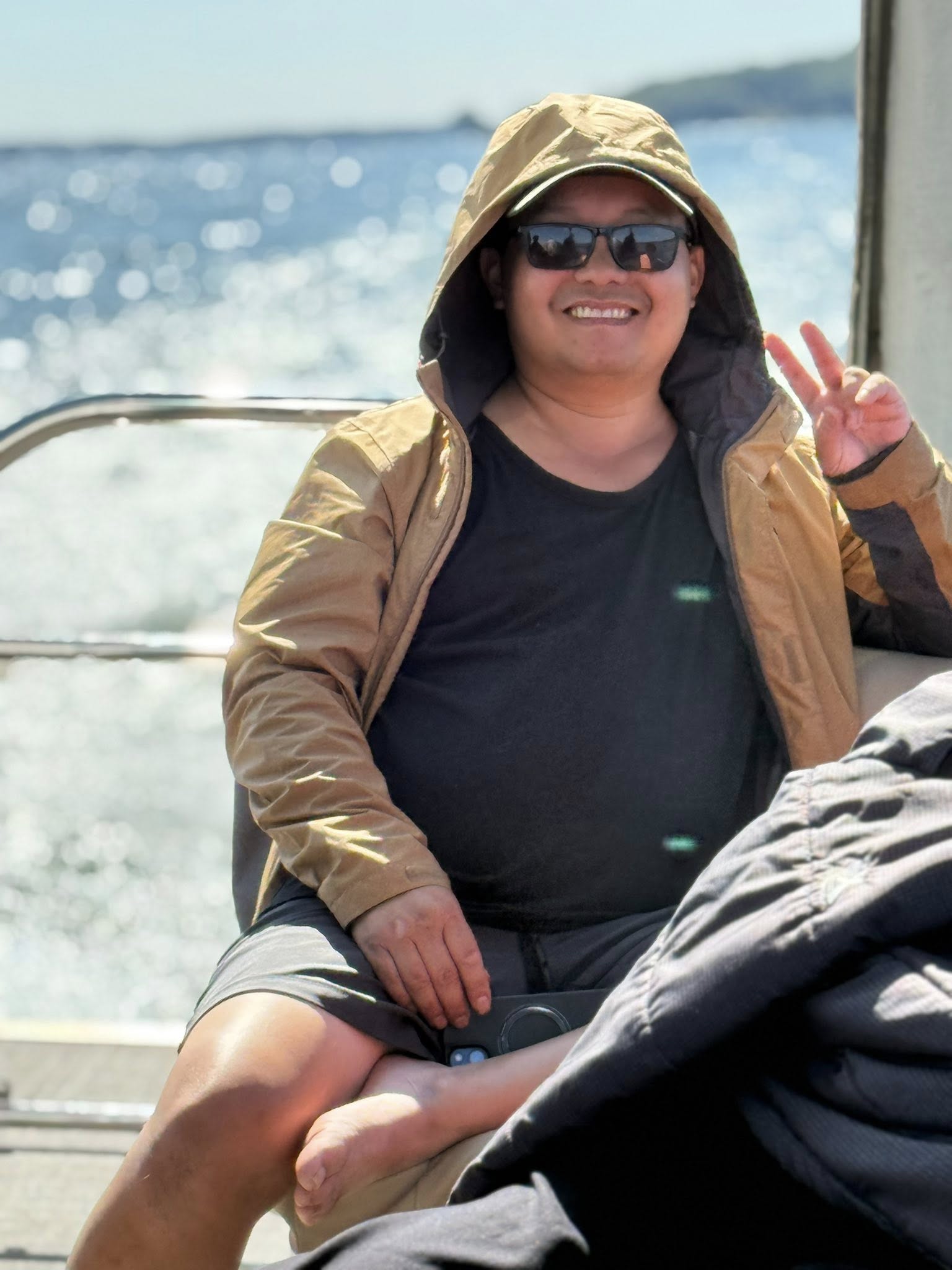 Brother smiling and making a peace sign on the boat